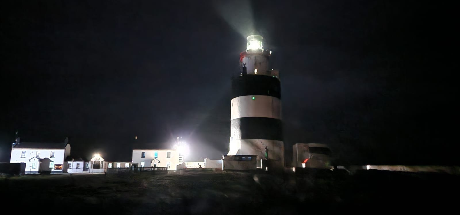 Hook Head lighthouse lit at night above the white keepers houses
