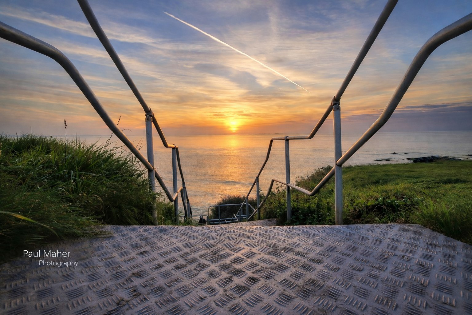 Steps and railings leading down to an Irish strand at sunrise