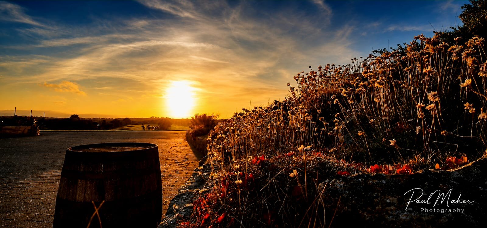 The sun setting behind an old stone harbour wall